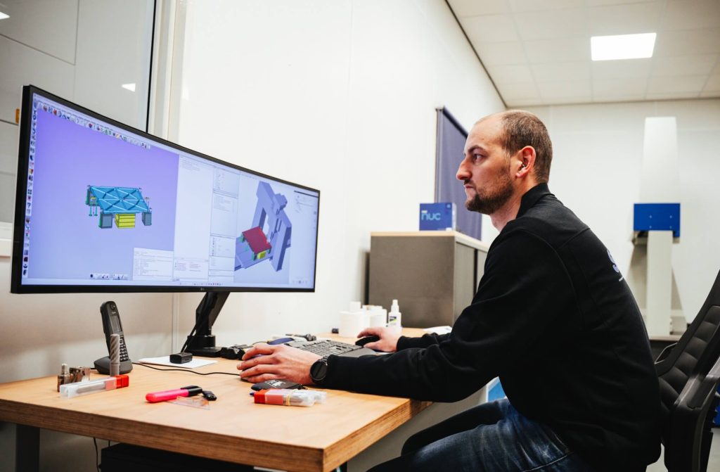 Ontwerper werkt aan 3D-model op groot scherm.